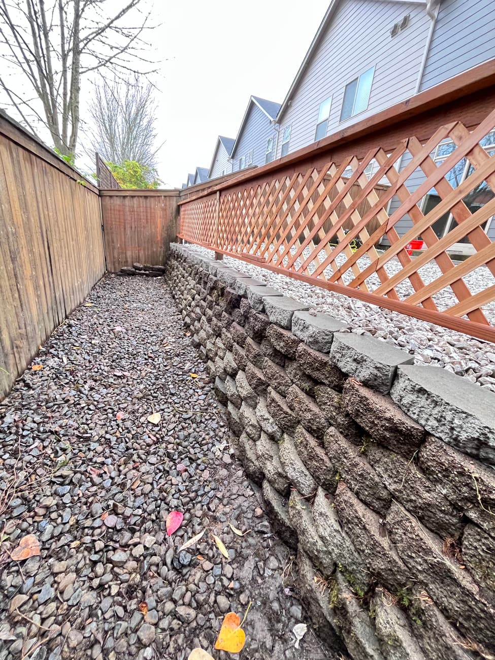 Boundary fence with lattice top above a stone retaining edge and gravel