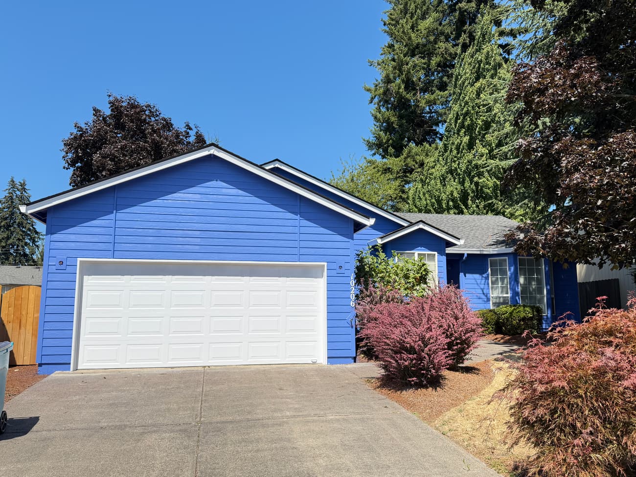 Completed exterior repaint: blue house, white garage door and driveway